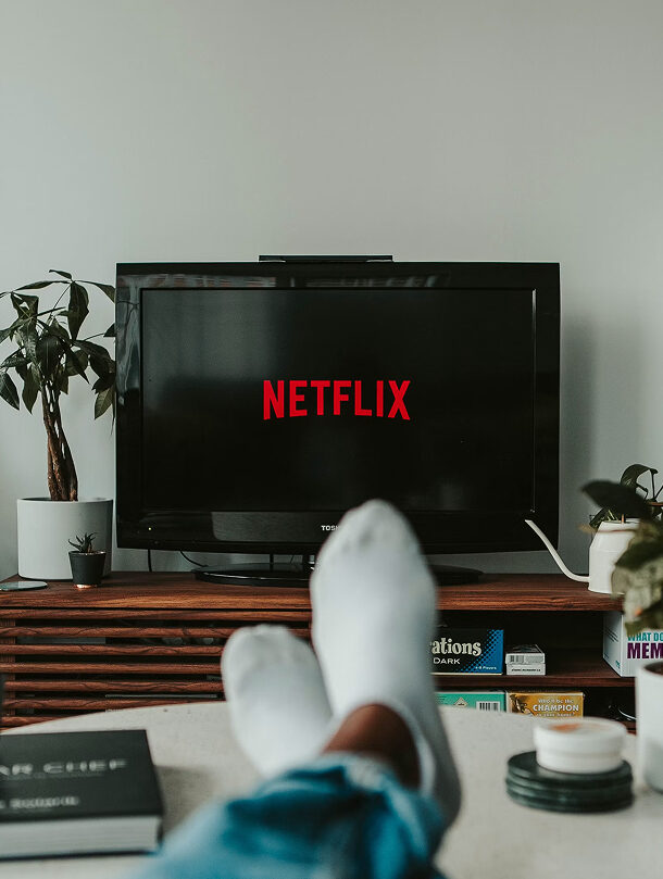 Person sitting with feet up and the Netflix loading screen display on their TV.